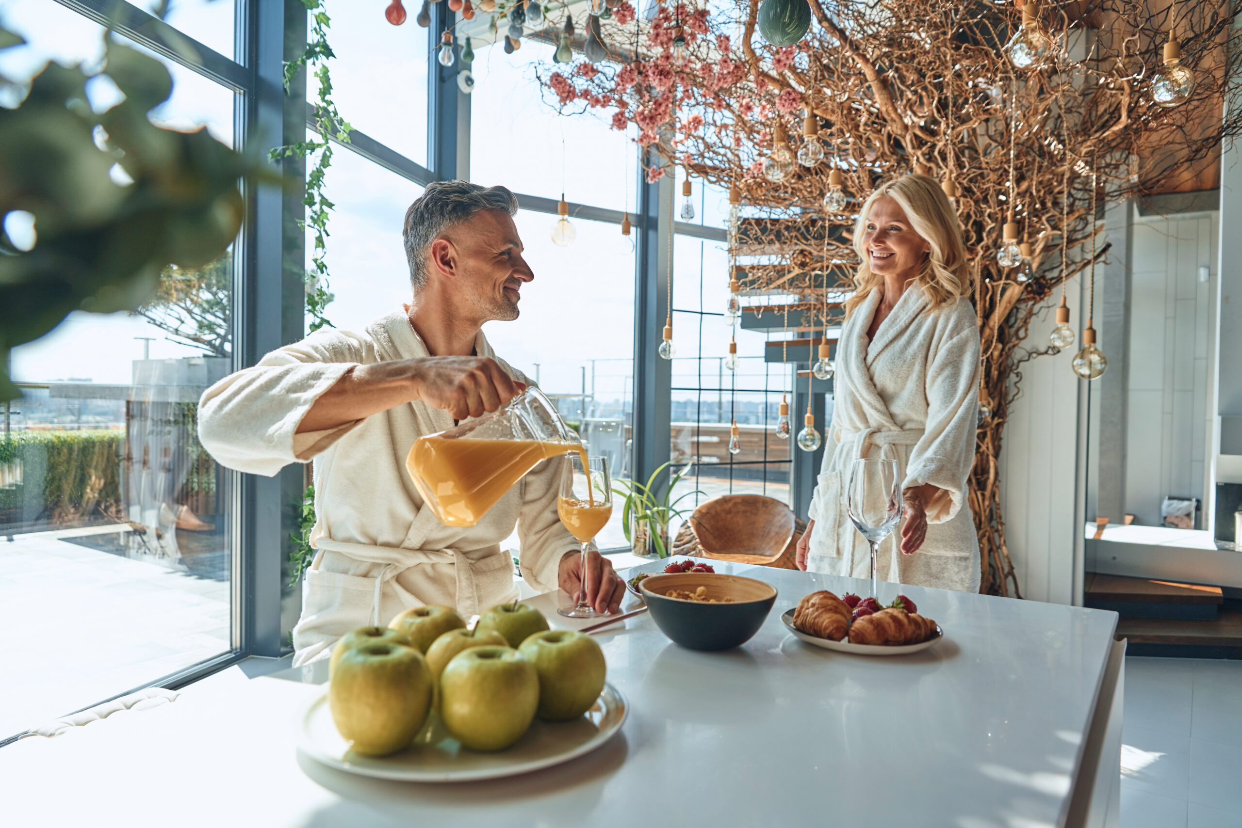 Beautiful mature couple in bathrobes enjoying breakfast together